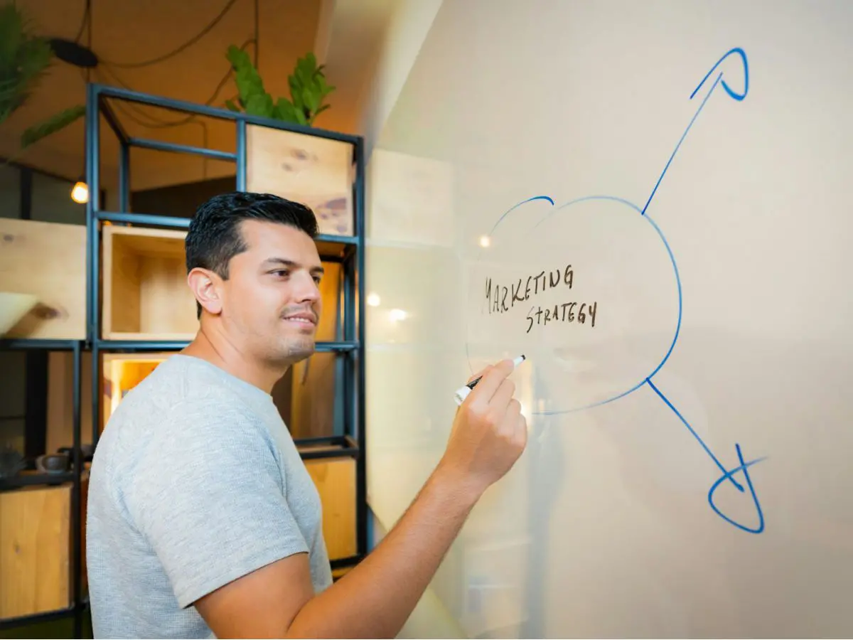 Homem desenhando um esquema de estratégia de marketing num quadro branco